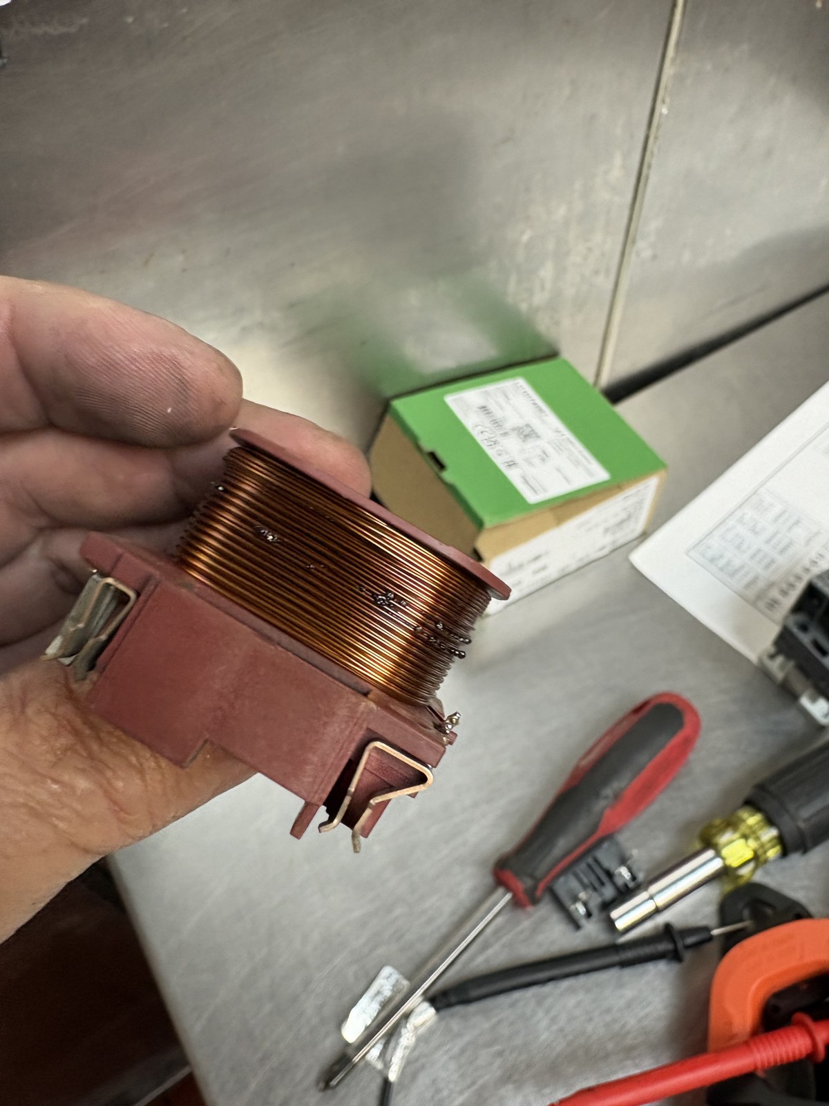 Removed contactor coil showing dark burn marks on the copper windings